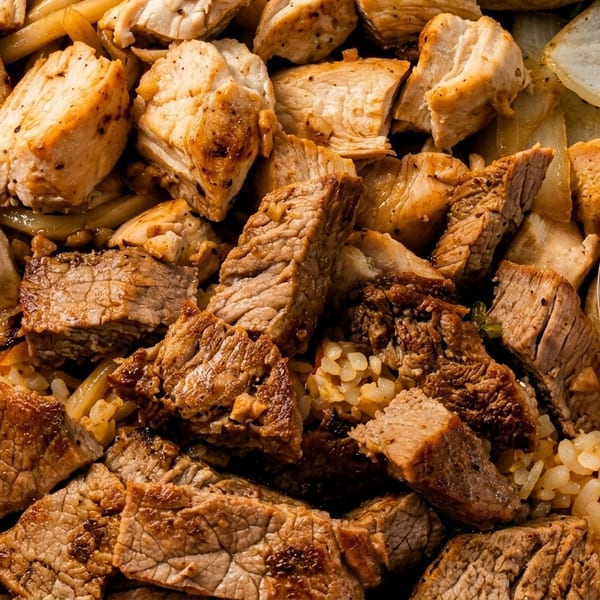 Close-up of a takeout container filled with grilled chicken, steak, noodles, rice, and vegetables.